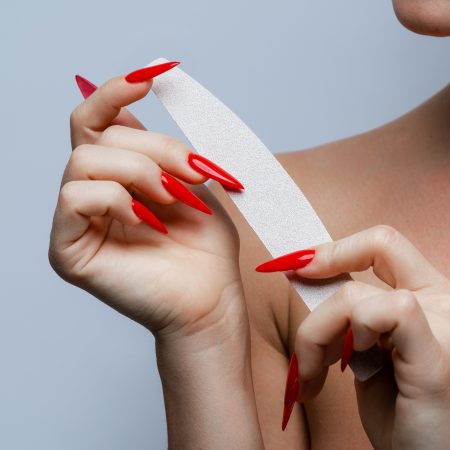 Graceful Hands with Red Stiletto Nails Holding Nail File